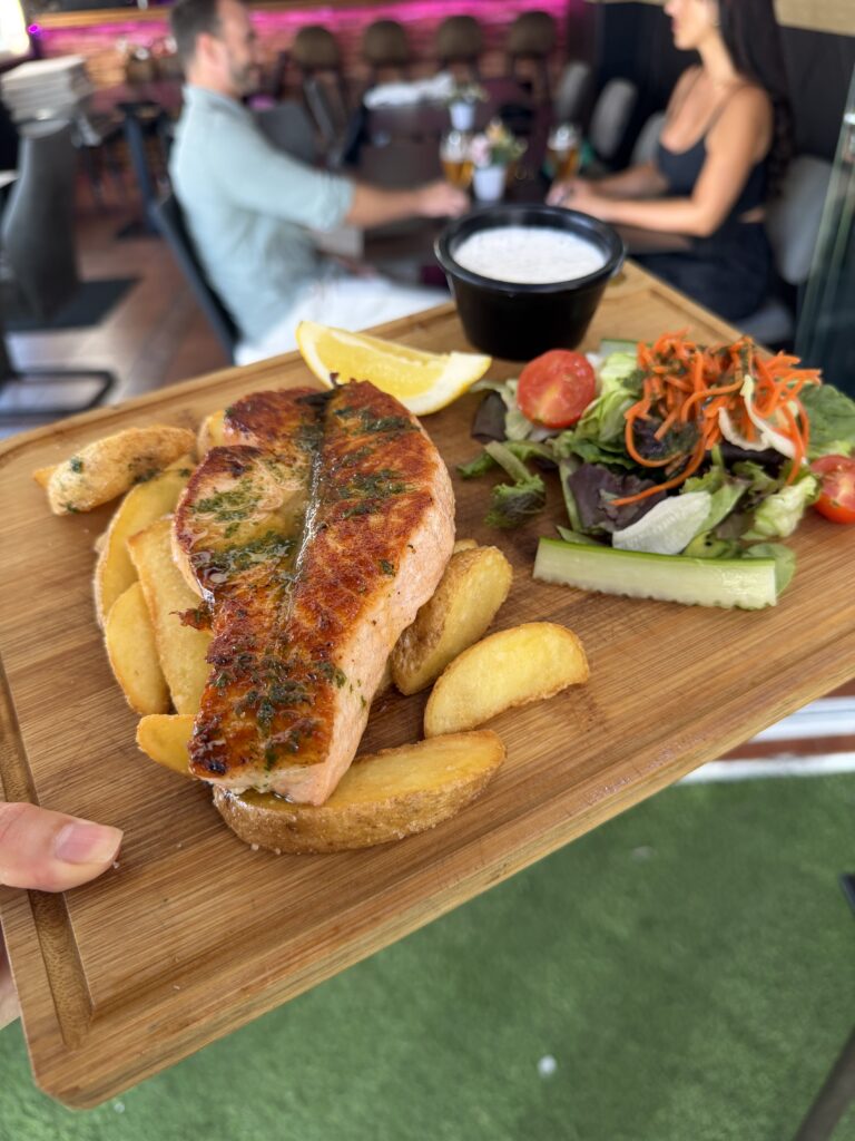 Salmon served with potato wedges and salad at Club Room 1